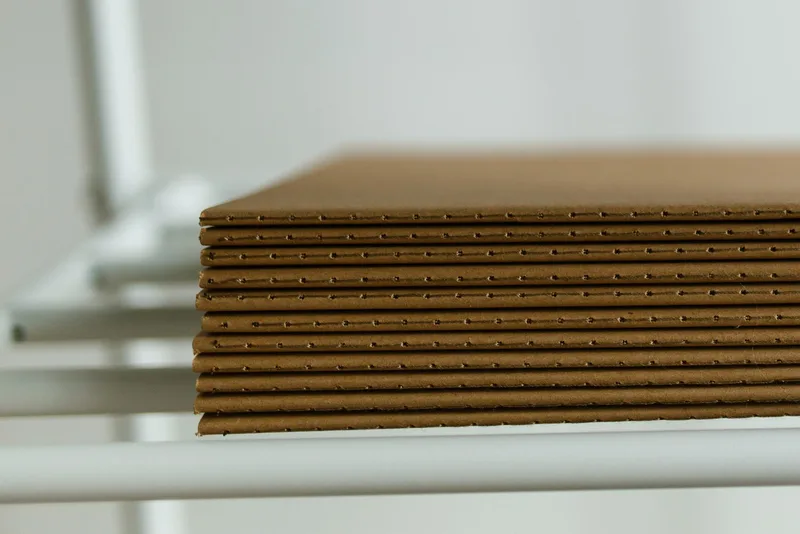 Neatly stacked corrugated cardboard sheets showing the fluted edge, ready for cutting and printing