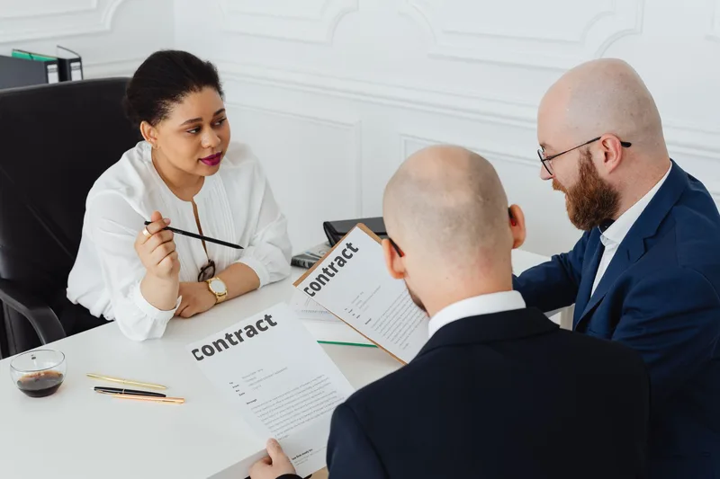 Business professionals discuss the terms of a supplier contract in an office