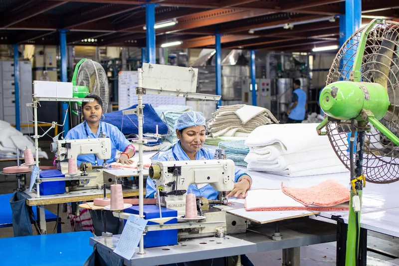 Factory workers operate sewing machines on a textile production line