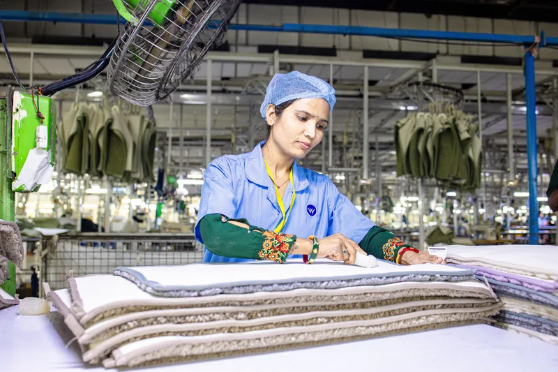 A textile factory worker inspecting fabric products for quality