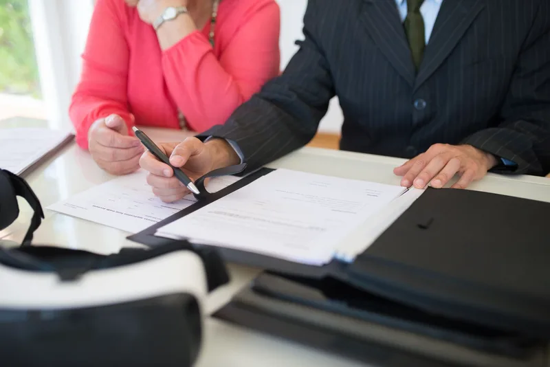 Close-up of professionals signing a business contract indoors, emphasizing agreement and documentation